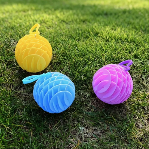 The Chroma Coil collection in Yellow, Blue, and Pink displayed on green grass - Adaptive sensory flex spheres by Lumenly